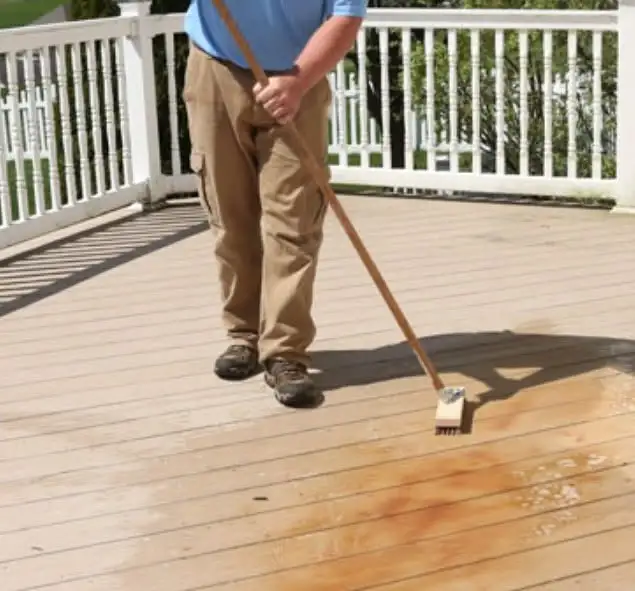 Technician scrubbing tannin and rust stains off a deck