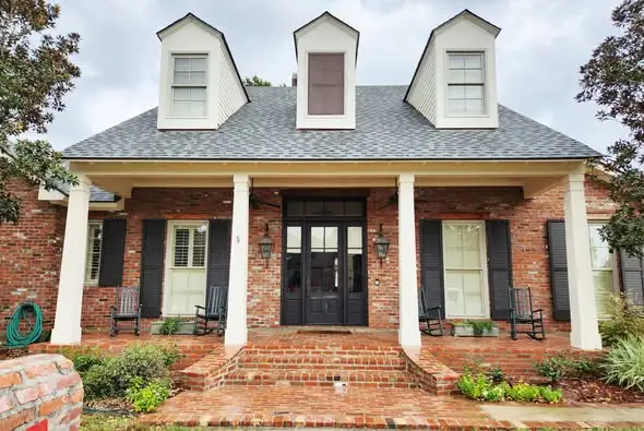 Dallas House Washing 4 Red brick home with black shutters, dormers, and white porch columns