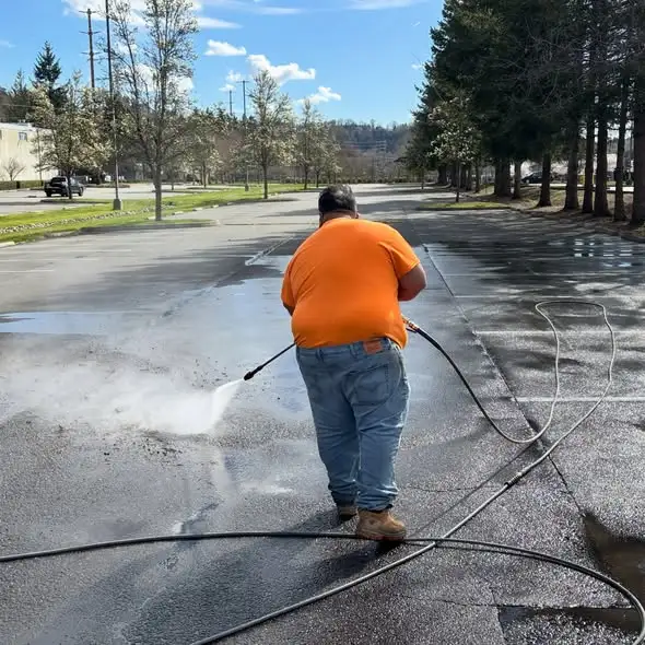 Irving pressure washer operator cleaning a commercial parking lot with a spray wand
